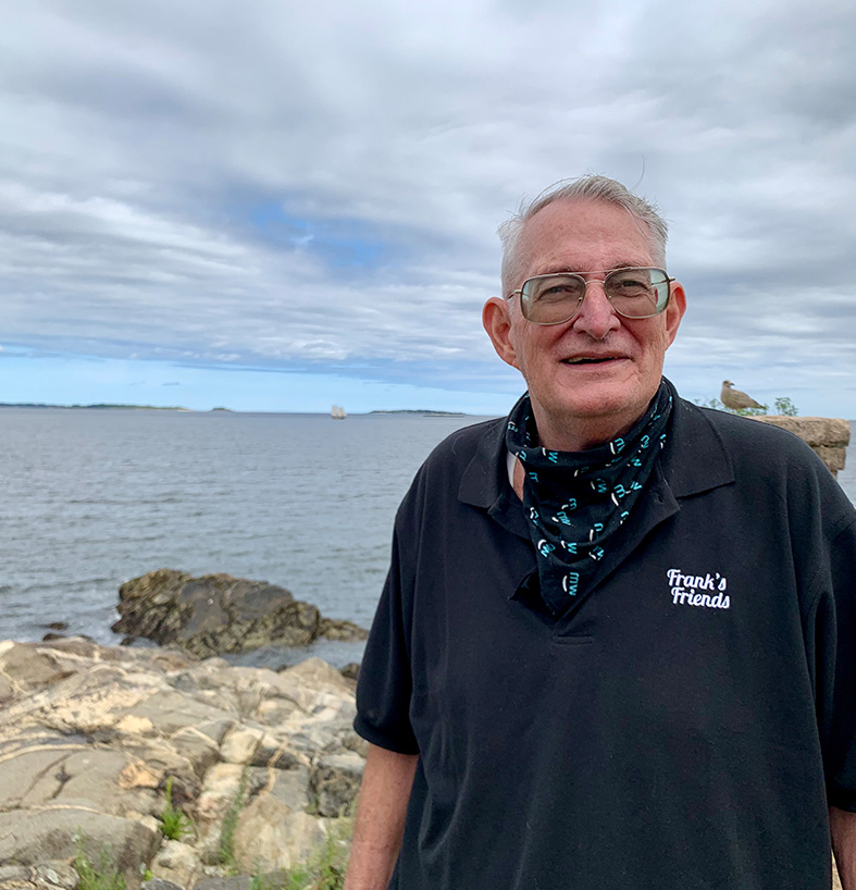 Frank stands by the ocean in his Frank's Friends Polo Shirt.